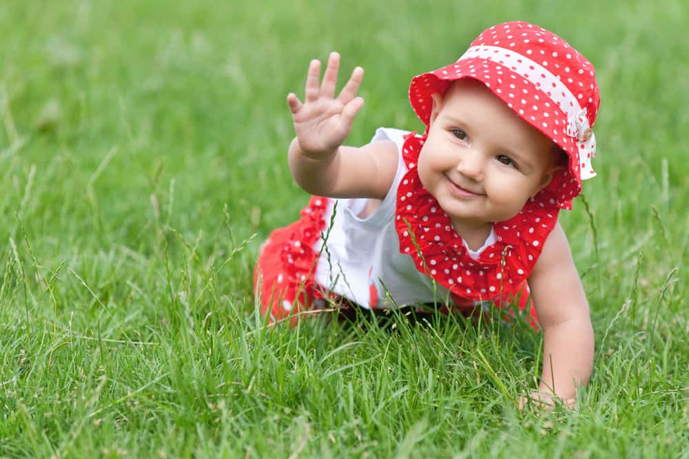 Baby girl on green organic lawn.