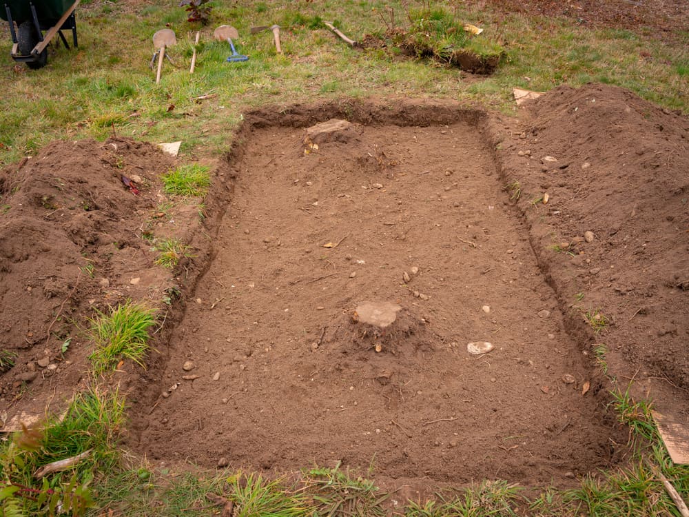 A square dug out in a yard for preparing Hügelkultur gardening.