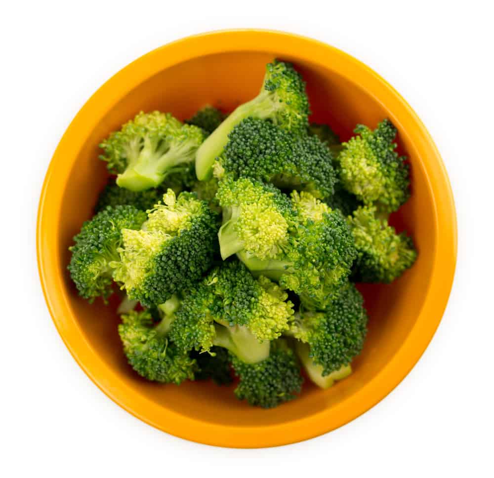 Fresh broccoli florets in a bowl on white background.