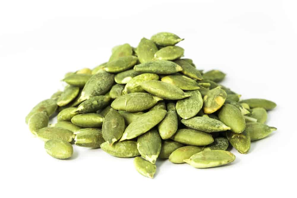 A pile of pumpkin seeds on a white background.